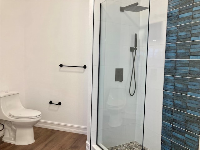 bathroom with hardwood / wood-style floors, toilet, and a tile shower