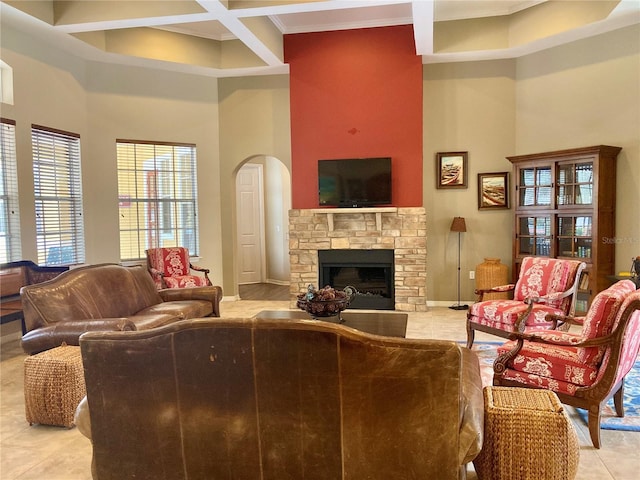 living room with a fireplace, light tile patterned flooring, a towering ceiling, and ornamental molding