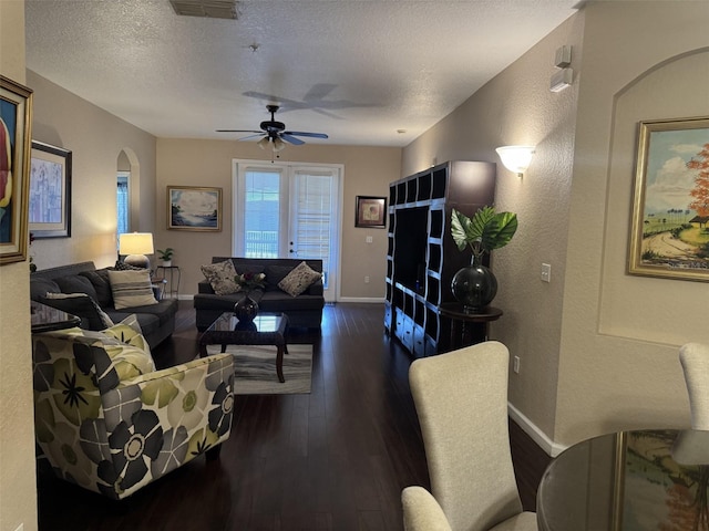 living room with ceiling fan, dark wood-type flooring, and a textured ceiling