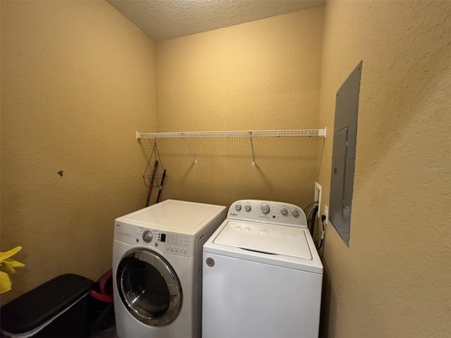 clothes washing area featuring washing machine and dryer, electric panel, and a textured ceiling