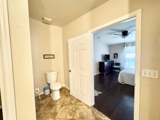 bathroom featuring ceiling fan, a textured ceiling, toilet, and hardwood / wood-style floors