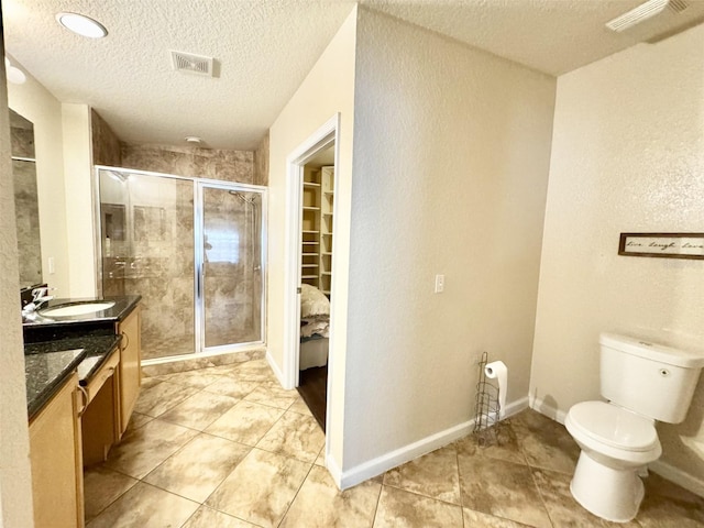 bathroom with a textured ceiling, toilet, walk in shower, and vanity