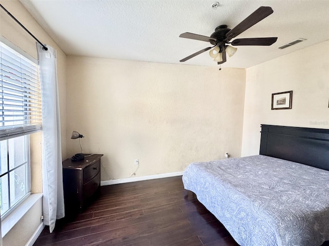 bedroom with a textured ceiling, ceiling fan, and dark hardwood / wood-style flooring