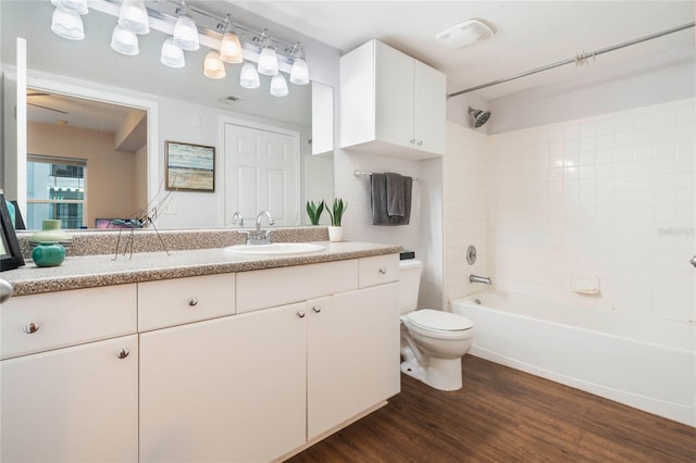 full bathroom featuring wood-type flooring, toilet, tiled shower / bath, and vanity