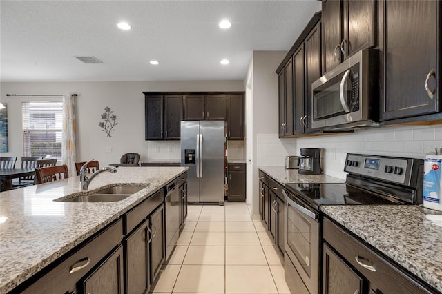 kitchen featuring light stone countertops, stainless steel appliances, tasteful backsplash, and sink