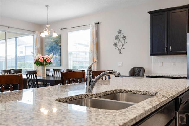 kitchen with sink, light stone counters, and pendant lighting