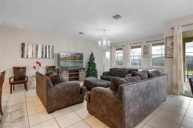 living room with a textured ceiling, an inviting chandelier, and light tile patterned floors