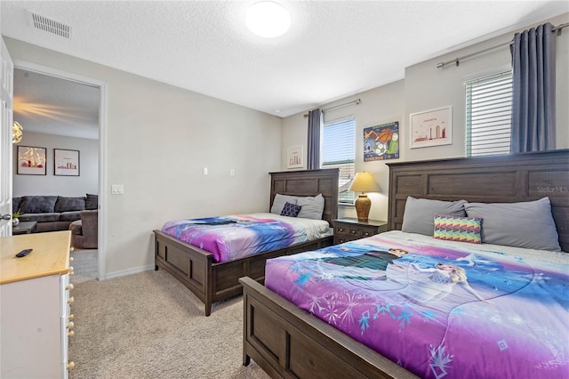 bedroom with light colored carpet and a textured ceiling