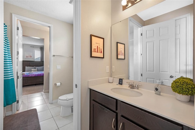 bathroom with toilet, vanity, tile patterned flooring, and a textured ceiling