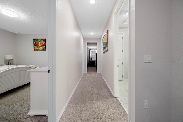 corridor featuring light carpet and a textured ceiling