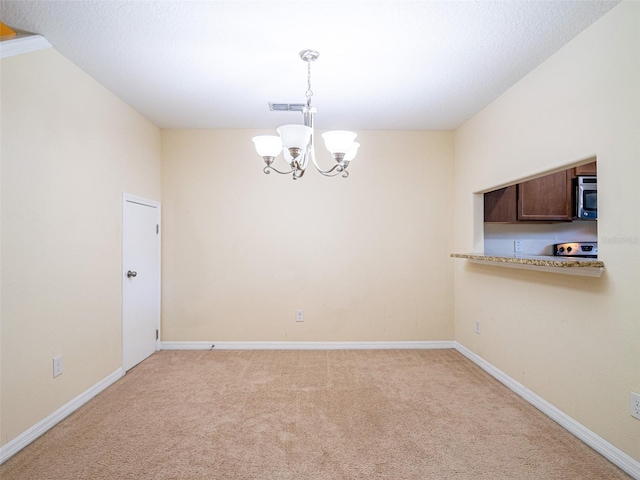 carpeted spare room with a notable chandelier