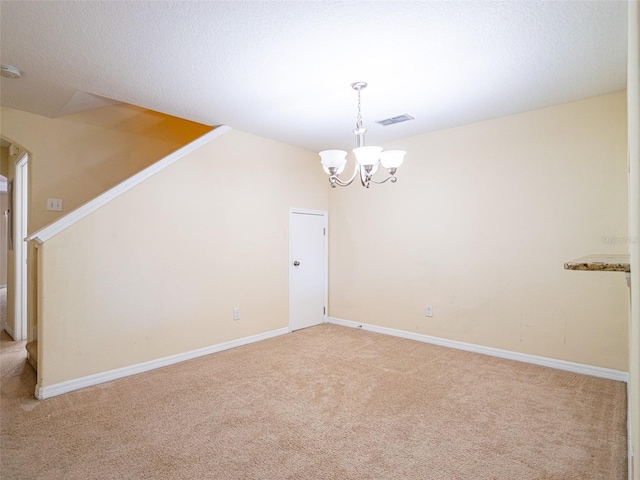 carpeted empty room featuring a notable chandelier