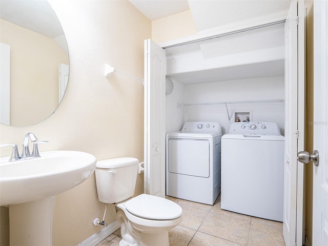 bathroom featuring washing machine and clothes dryer, tile patterned floors, toilet, and sink