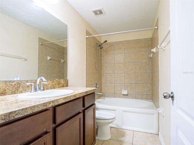 full bathroom featuring tile patterned flooring, tiled shower / bath combo, vanity, a textured ceiling, and toilet