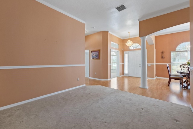 entryway with light colored carpet, ornamental molding, and ornate columns