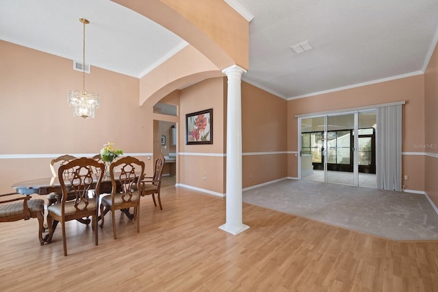 dining space featuring decorative columns, light wood-type flooring, ornamental molding, and an inviting chandelier