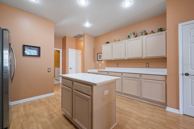 kitchen featuring tile countertops, light hardwood / wood-style floors, a center island, and stainless steel fridge