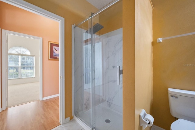 bathroom featuring toilet, a shower with shower door, and hardwood / wood-style flooring