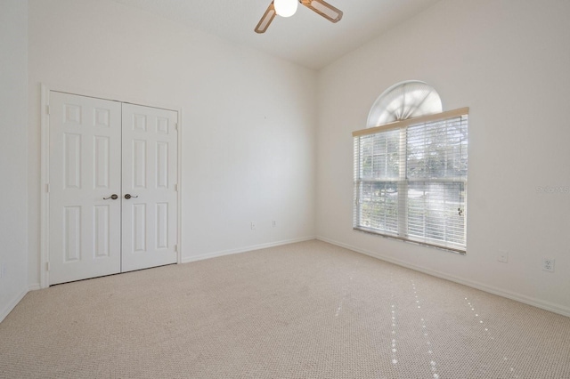 unfurnished room with ceiling fan, plenty of natural light, light colored carpet, and vaulted ceiling