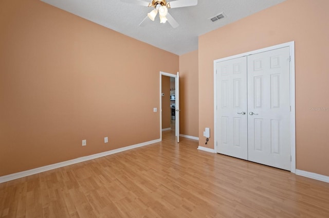 unfurnished bedroom featuring light hardwood / wood-style floors, a textured ceiling, a closet, and ceiling fan