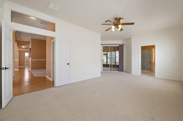 carpeted empty room with ceiling fan and ornamental molding