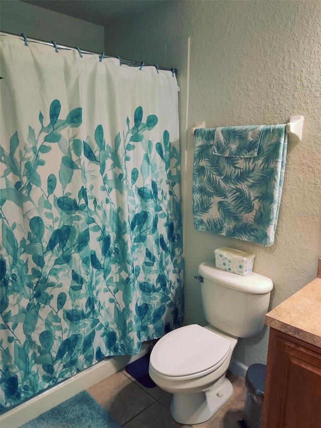 bathroom with toilet, vanity, and tile patterned flooring