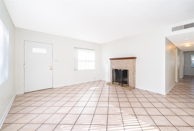 unfurnished living room featuring a brick fireplace and light tile patterned floors