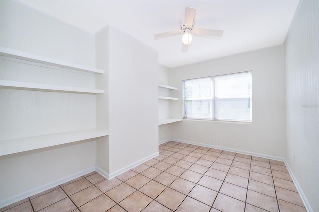 unfurnished room with light tile patterned floors, built in shelves, and ceiling fan