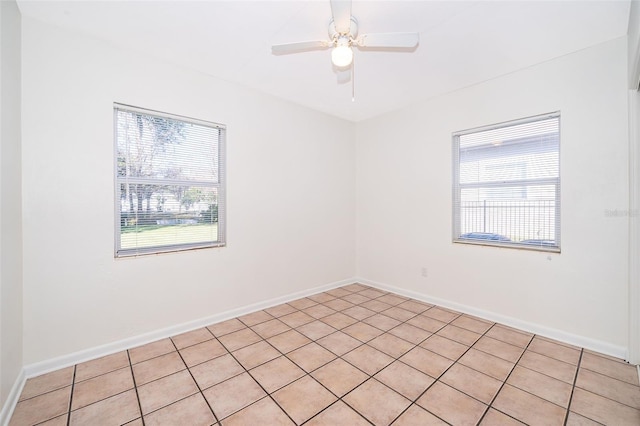 empty room with ceiling fan and light tile patterned floors