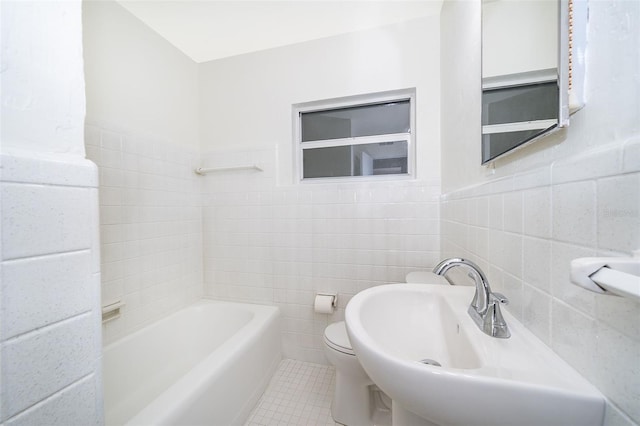 bathroom with tile patterned floors, toilet, sink, tile walls, and a washtub