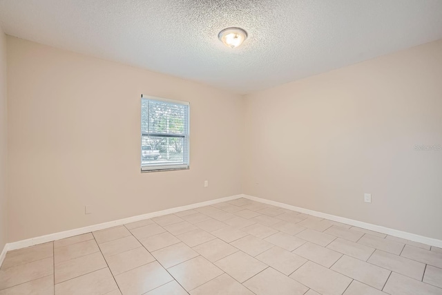 empty room featuring a textured ceiling and light tile patterned floors