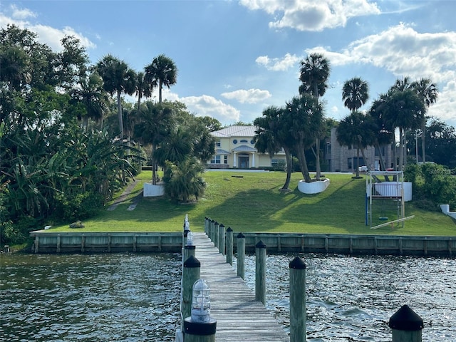 view of dock with a water view and a lawn