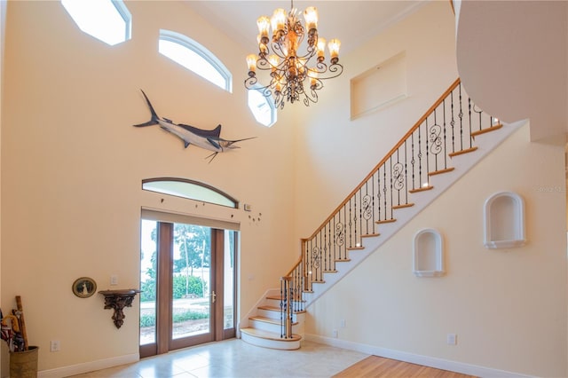 foyer entrance with crown molding, a towering ceiling, and a chandelier