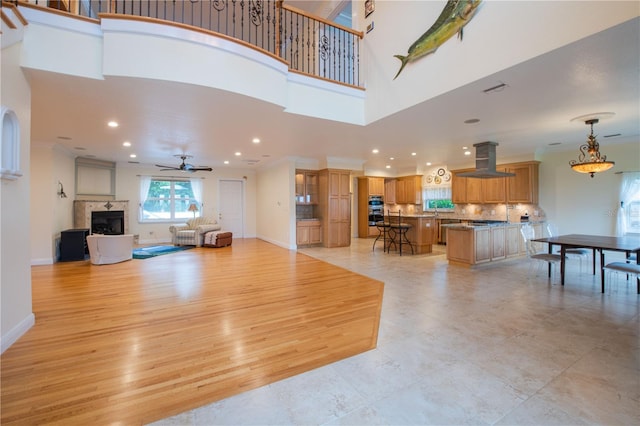 living room featuring a high ceiling, light wood-type flooring, and ceiling fan