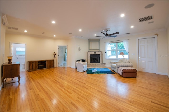 living room with ornamental molding, ceiling fan, and light wood-type flooring