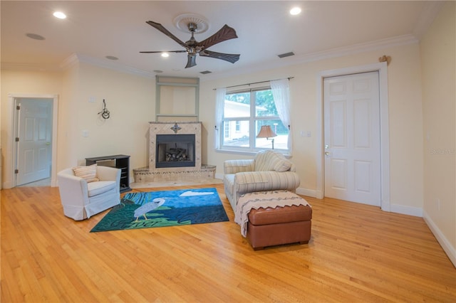 living room with ornamental molding, ceiling fan, and light hardwood / wood-style flooring