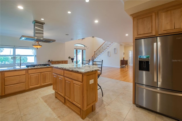 kitchen featuring a kitchen bar, a kitchen island, island exhaust hood, stainless steel appliances, and light stone countertops