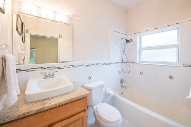 full bathroom with vanity, toilet, tiled shower / bath combo, and tile walls