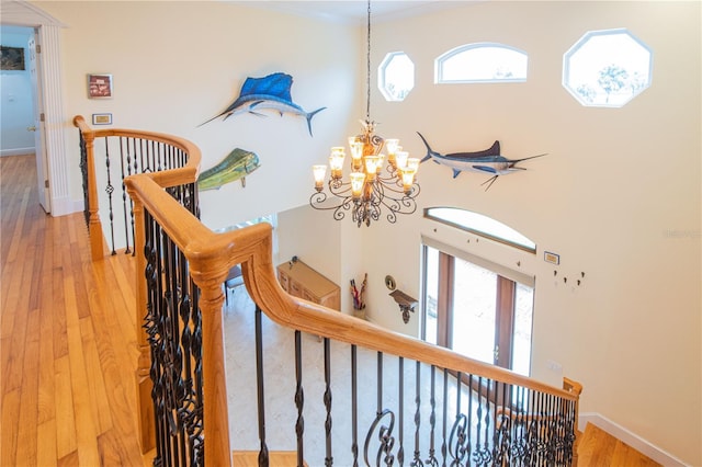 stairway with a notable chandelier, crown molding, and wood-type flooring