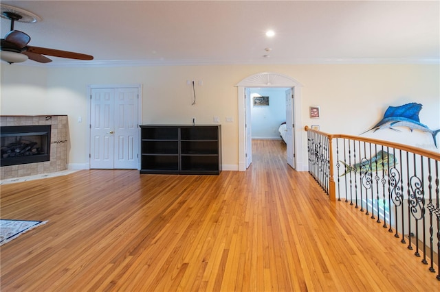 unfurnished living room featuring a fireplace, ornamental molding, light hardwood / wood-style floors, and ceiling fan