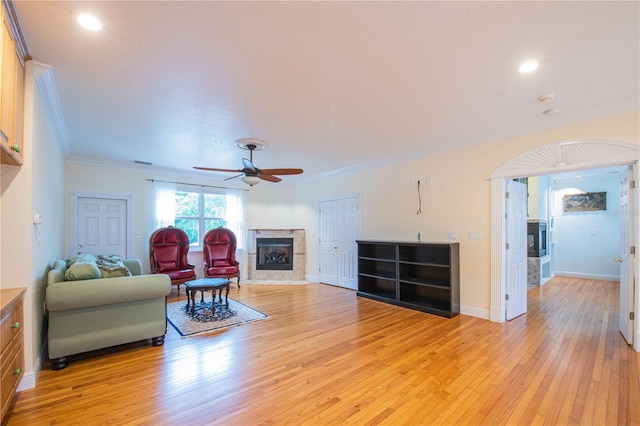 living room featuring ornamental molding, ceiling fan, and light wood-type flooring