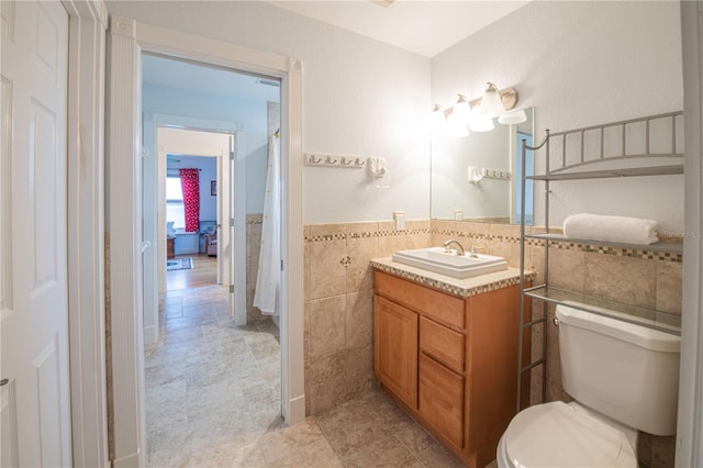 bathroom with tile walls, vanity, and toilet