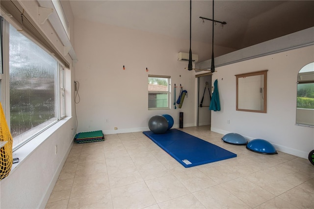 workout area featuring light tile patterned flooring, a healthy amount of sunlight, a wall mounted AC, and a towering ceiling