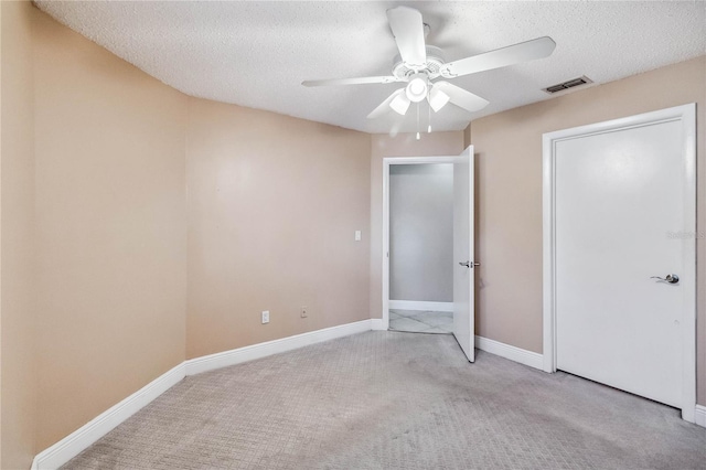 unfurnished bedroom with light colored carpet, a textured ceiling, and ceiling fan