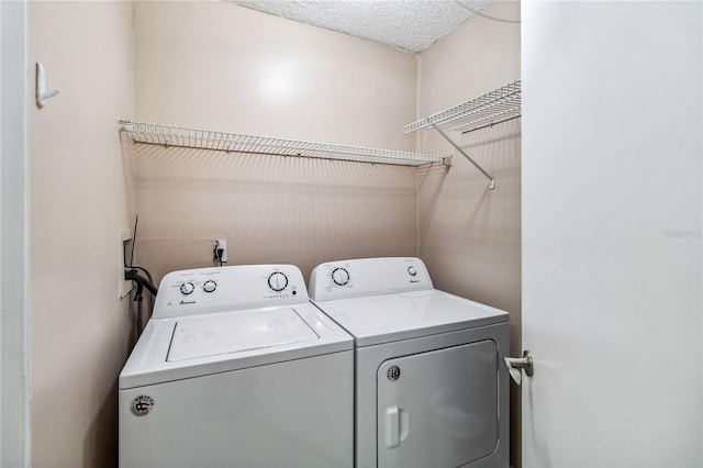 clothes washing area featuring washing machine and clothes dryer and a textured ceiling