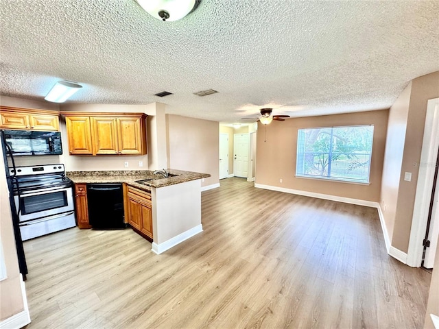 kitchen featuring stone countertops, a sink, open floor plan, black appliances, and light wood finished floors