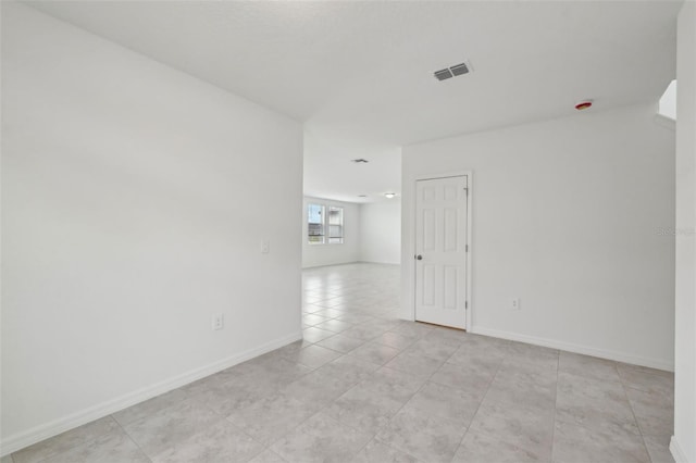 empty room featuring visible vents, baseboards, and light tile patterned floors