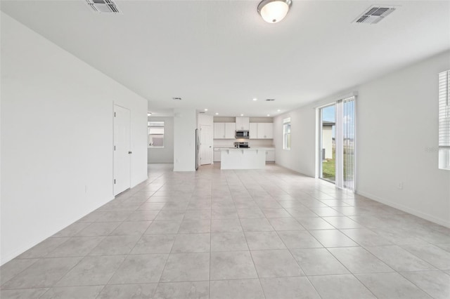 unfurnished living room featuring light tile patterned flooring, visible vents, and recessed lighting