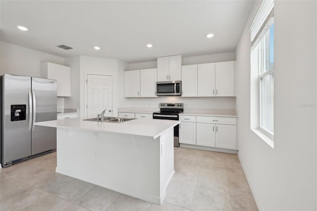 kitchen with a center island with sink, stainless steel appliances, light countertops, white cabinetry, and a sink