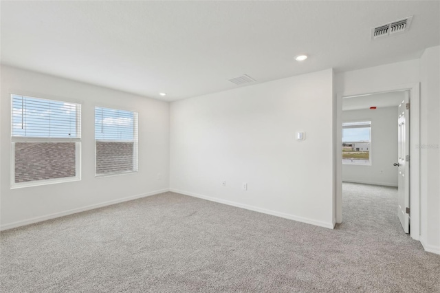 unfurnished room featuring baseboards, visible vents, and light colored carpet